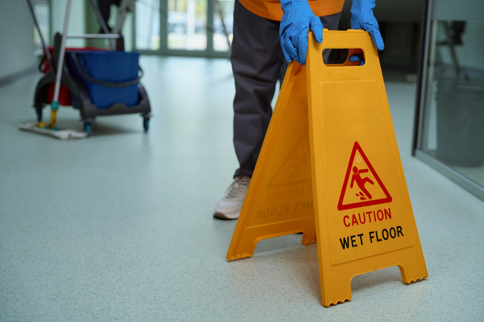 Mindful janitor putting plastic caution sign on the wet floor